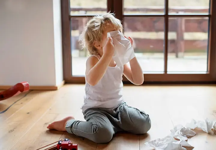 Young child holding a tissue to their face