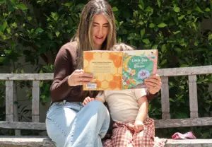 Carly Kremer reading a nature book with her child outdoors