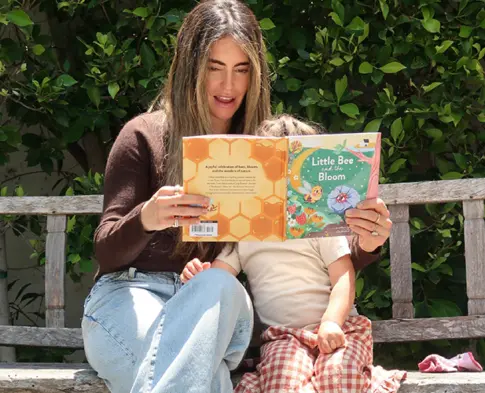 Carly Kremer reading a nature book with her child outdoors