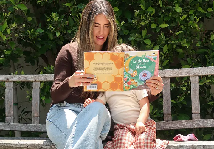 Carly Kremer reading a nature book with her child outdoors