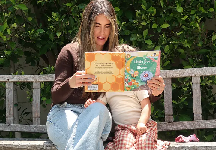Carly Kremer reading a nature book with her child outdoors
