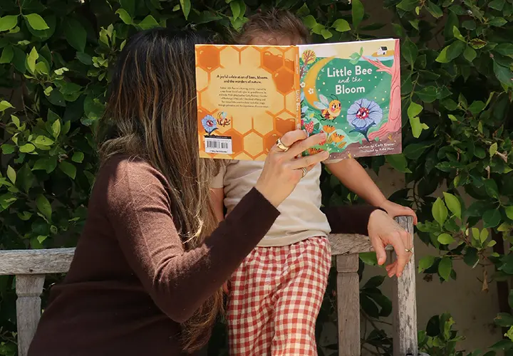 Carly Kremer reading Little Bee in Bloom with her child outdoors