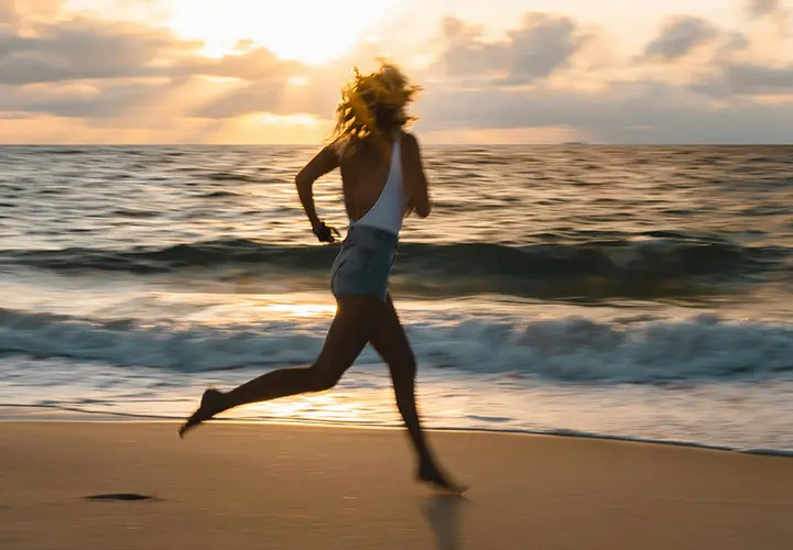 Woman running on the beach at sunset