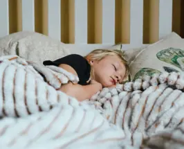 Young child sleeping in bed under a blanket