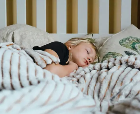 Young child sleeping in bed under a blanket