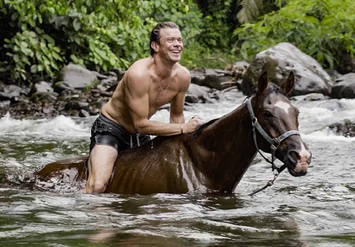 Guest riding a horse through a river at The Vessyl in Costa Rica
