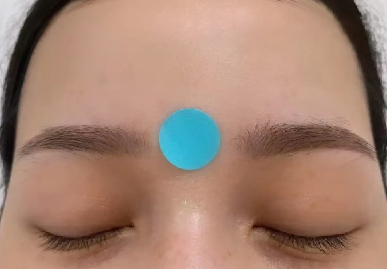 Yintang acupressure point between the eyebrows used in a TCM relaxation practice